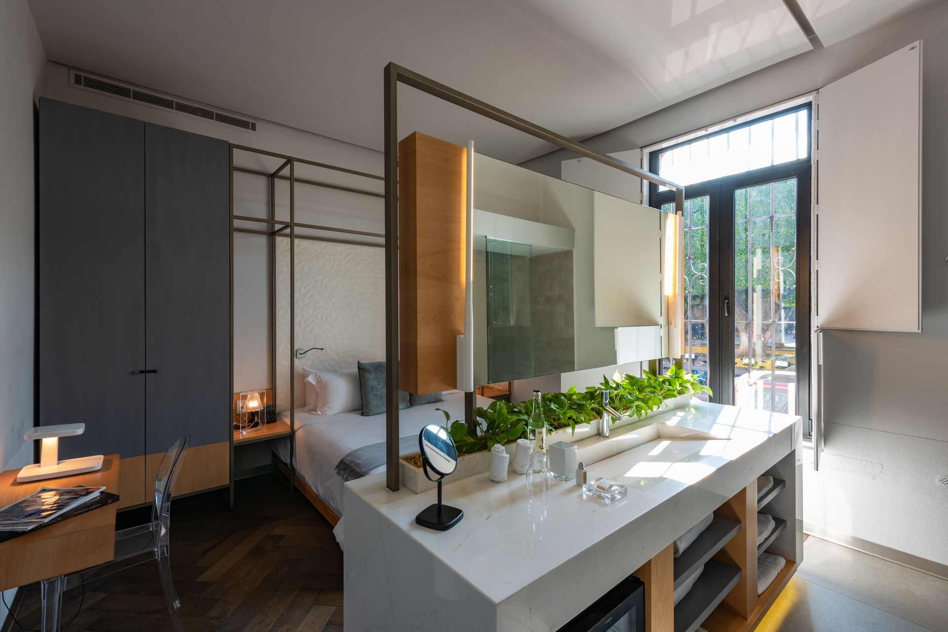 Un dormitorio con cama, escritorio, lavabo y espejo.