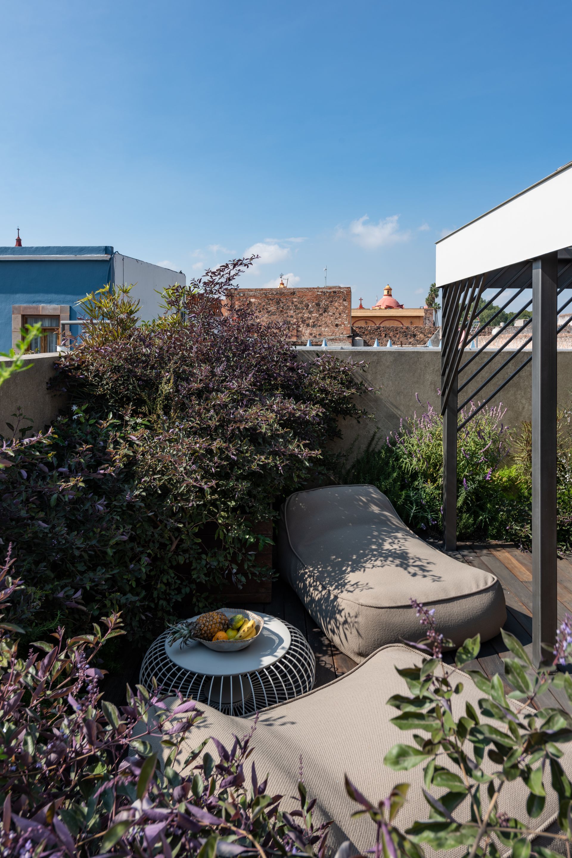 Un patio con un sofá y una mesa en medio de un jardín.