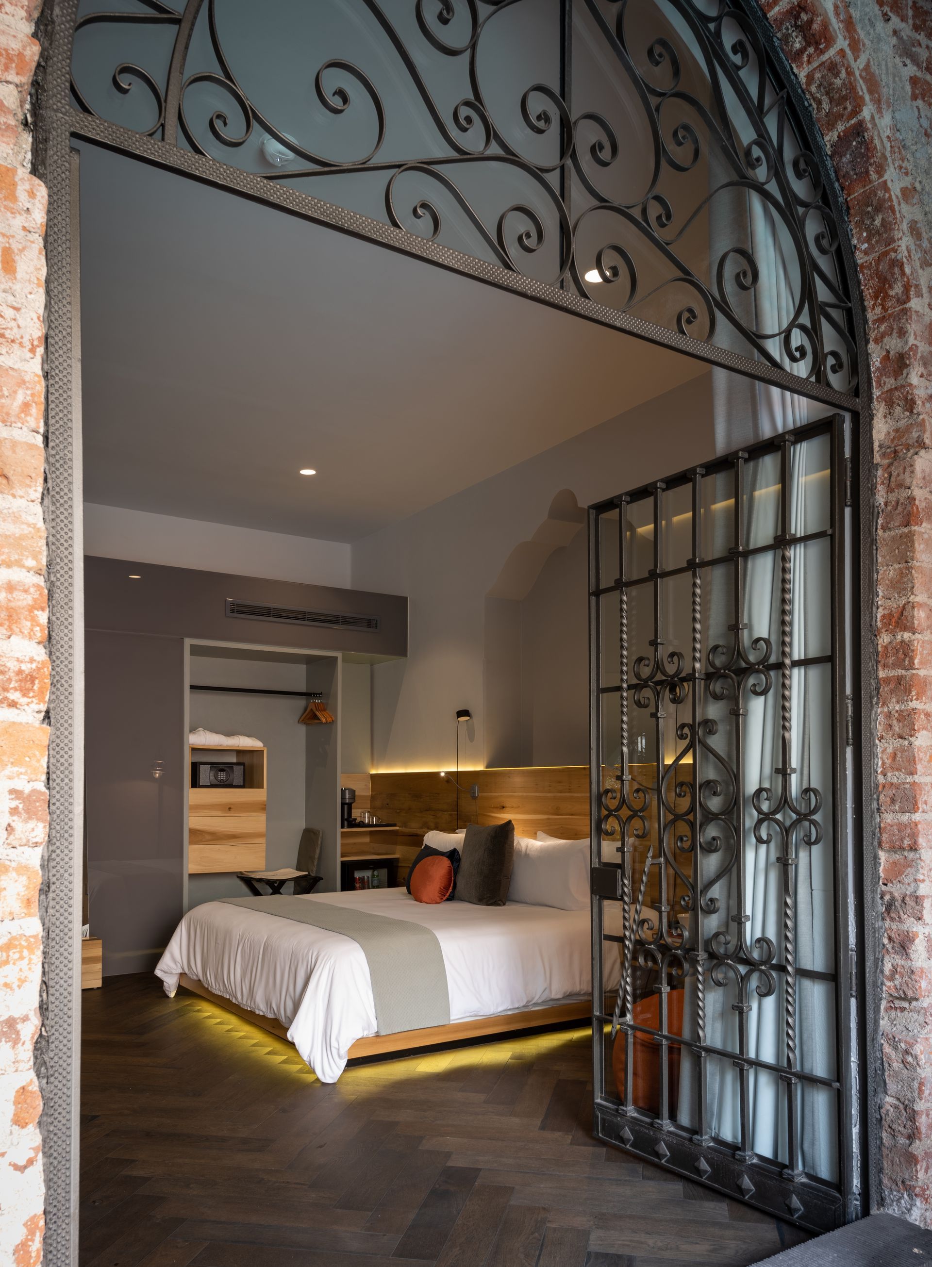 Una habitación de hotel con una cama y una puerta de hierro forjado.