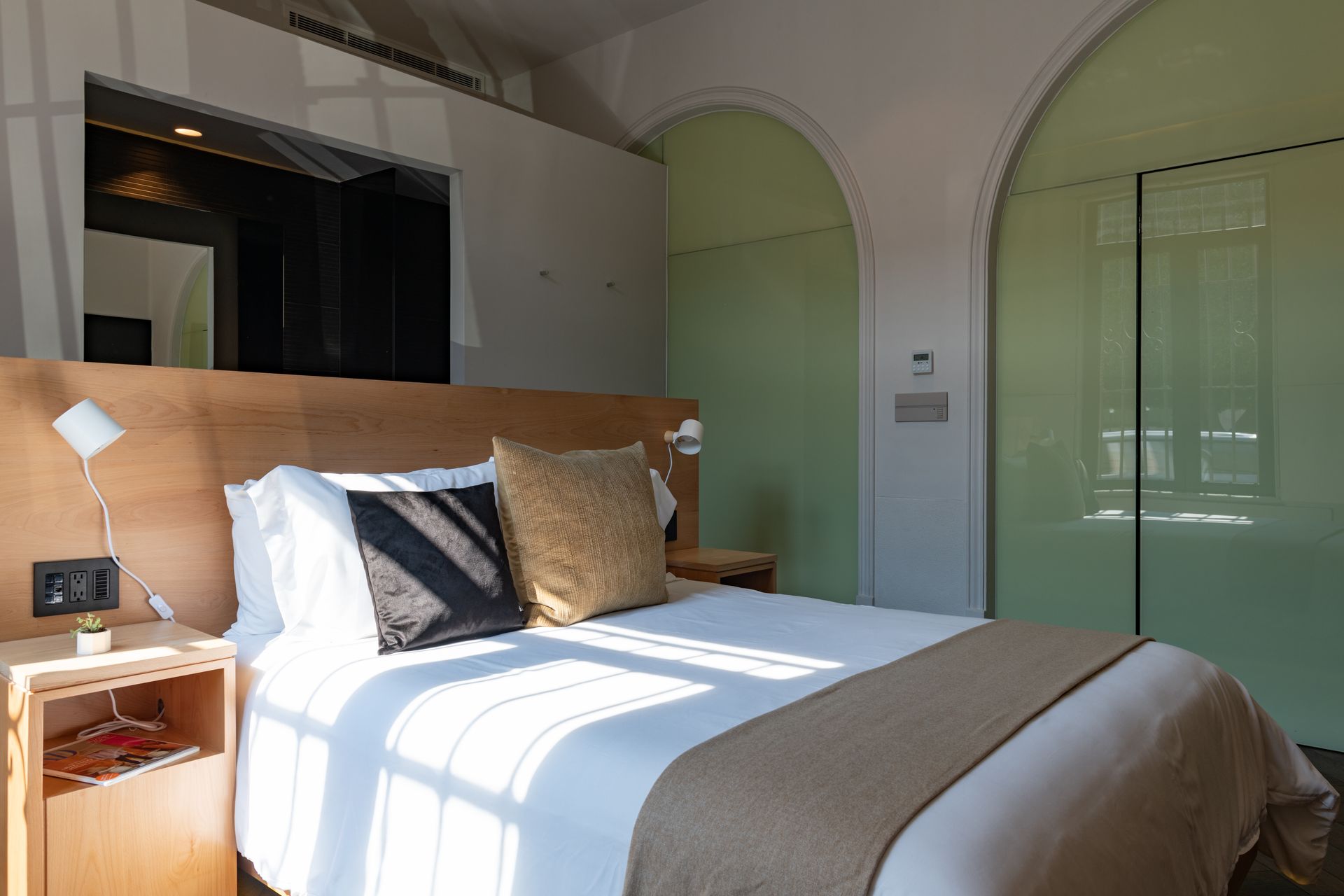 Una habitación de hotel con una cama grande y una puerta de cristal.