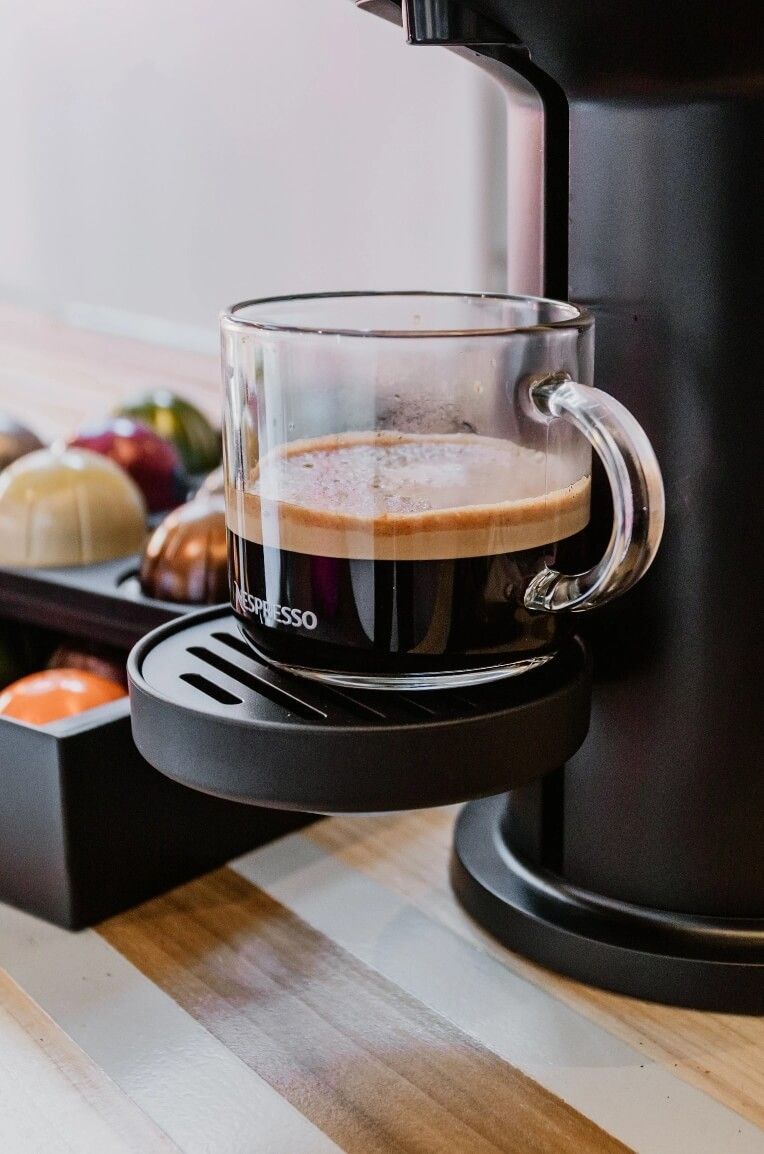 Se vierte una taza de café en una cafetera.