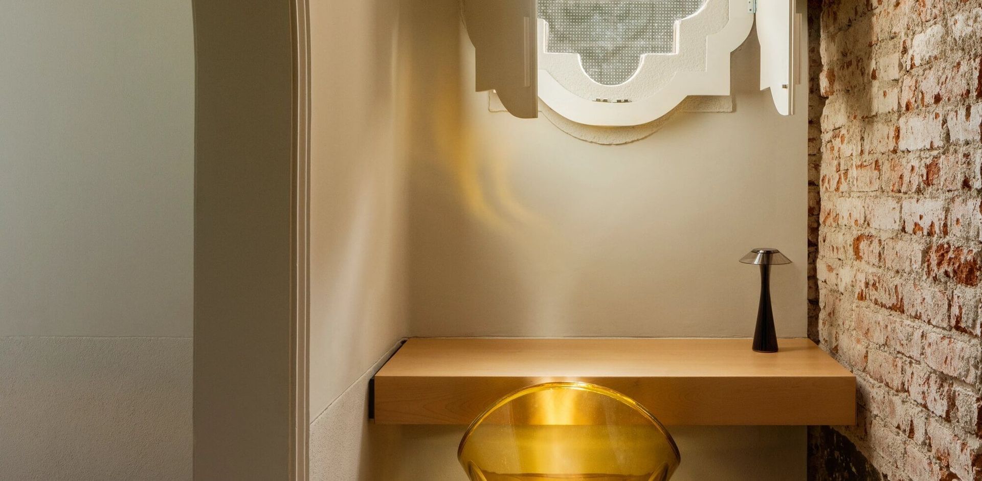 Una pequeña habitación con una pared de ladrillos y una mesa de madera.