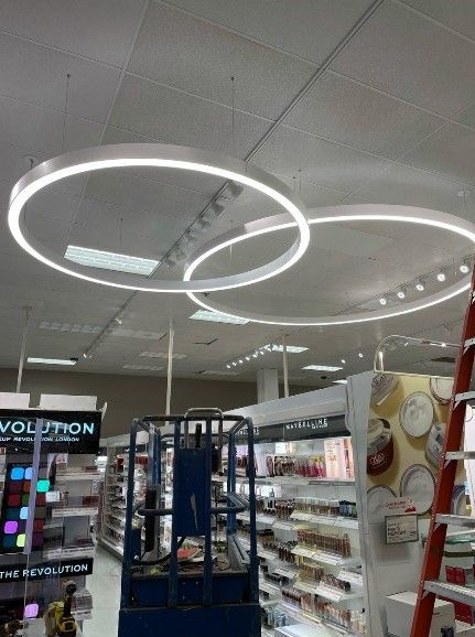 Two large, glowing circular pendant lights suspended from the ceiling in a retail store aisle.