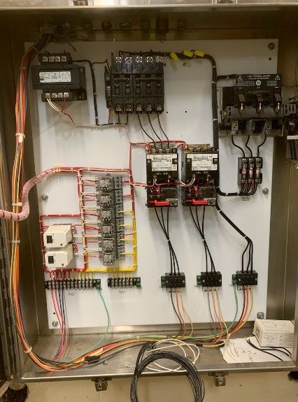 Two workers in hard hats install blue solar panels on a metal frame under a clear blue sky.