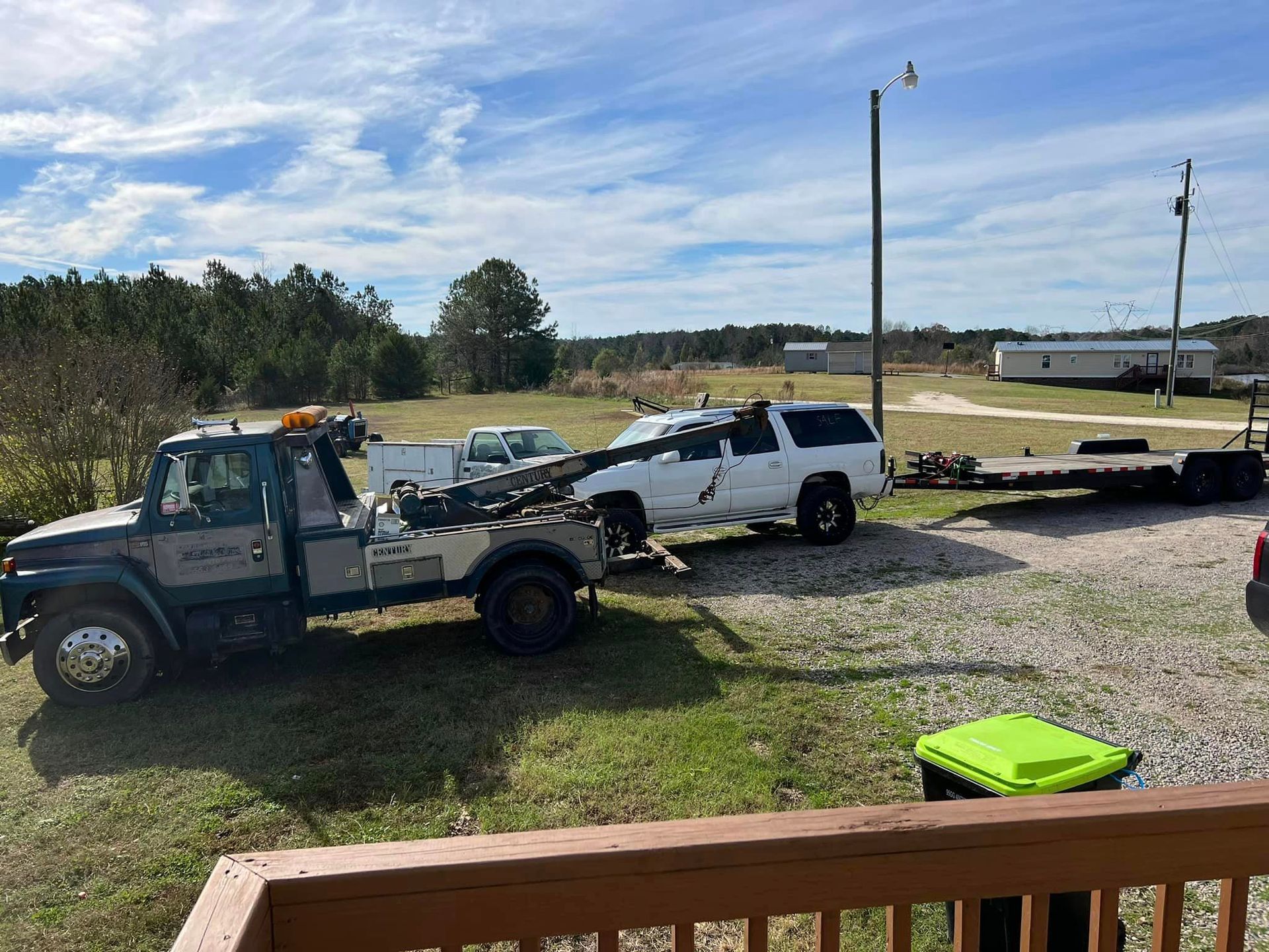 A tow truck is towing a white truck on a trailer.