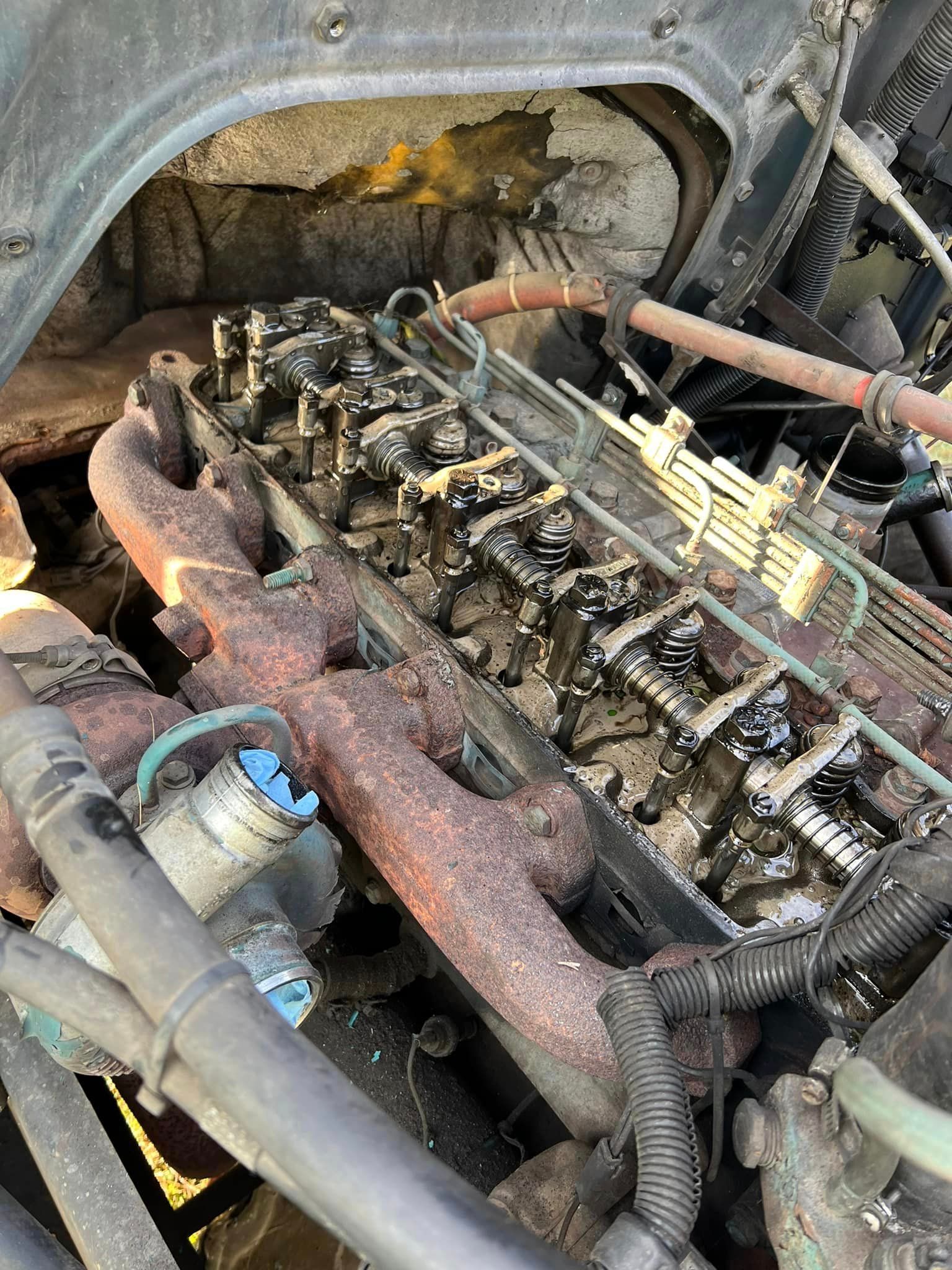A close up of a rusty engine with a hose coming out of it.