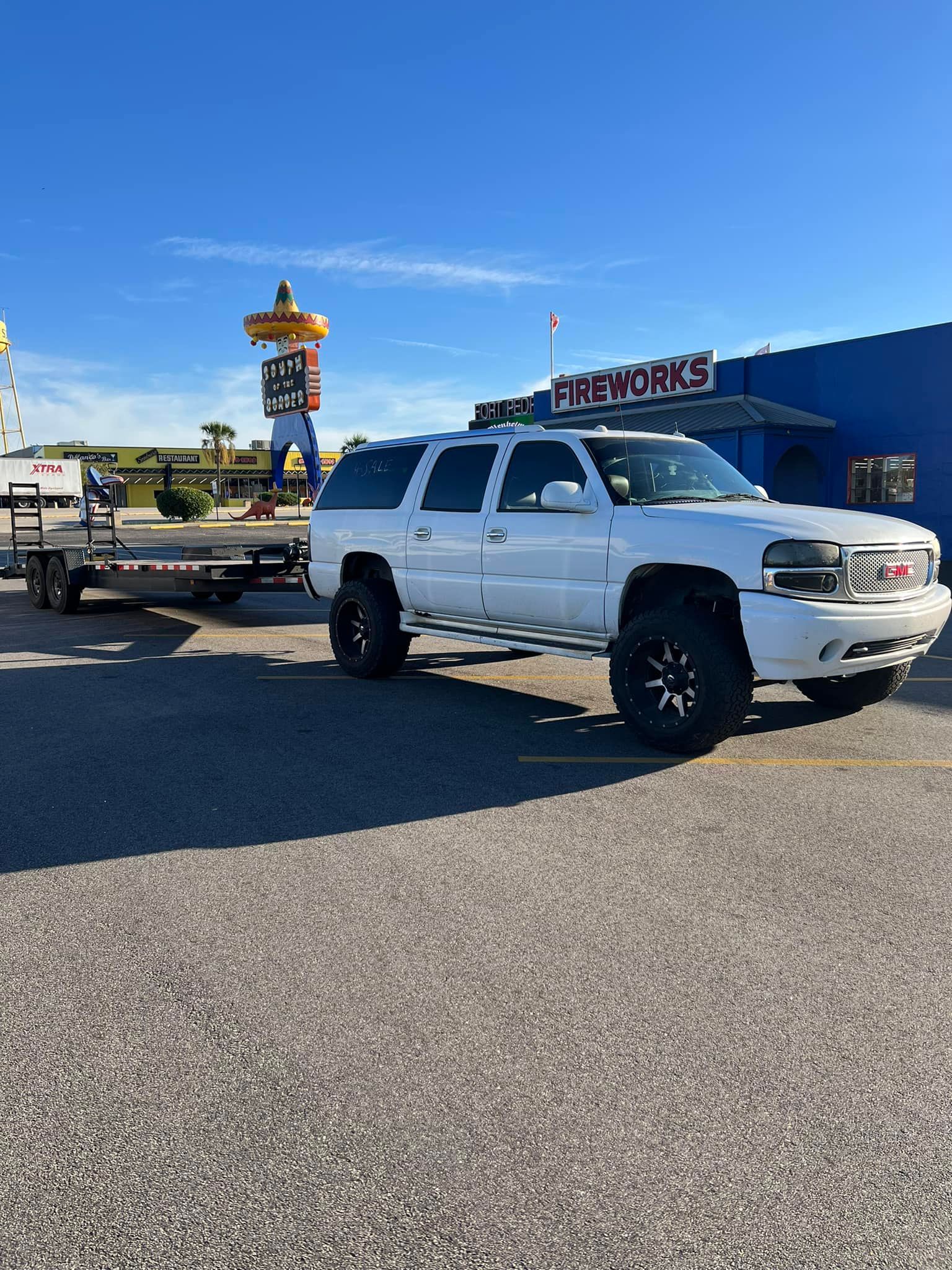 A white suv is being towed by a trailer.