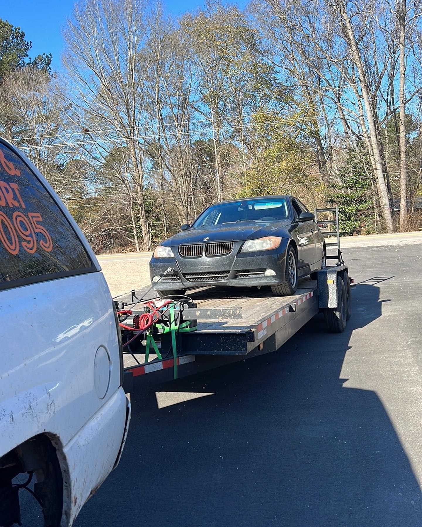 A black car is being towed by a tow truck.