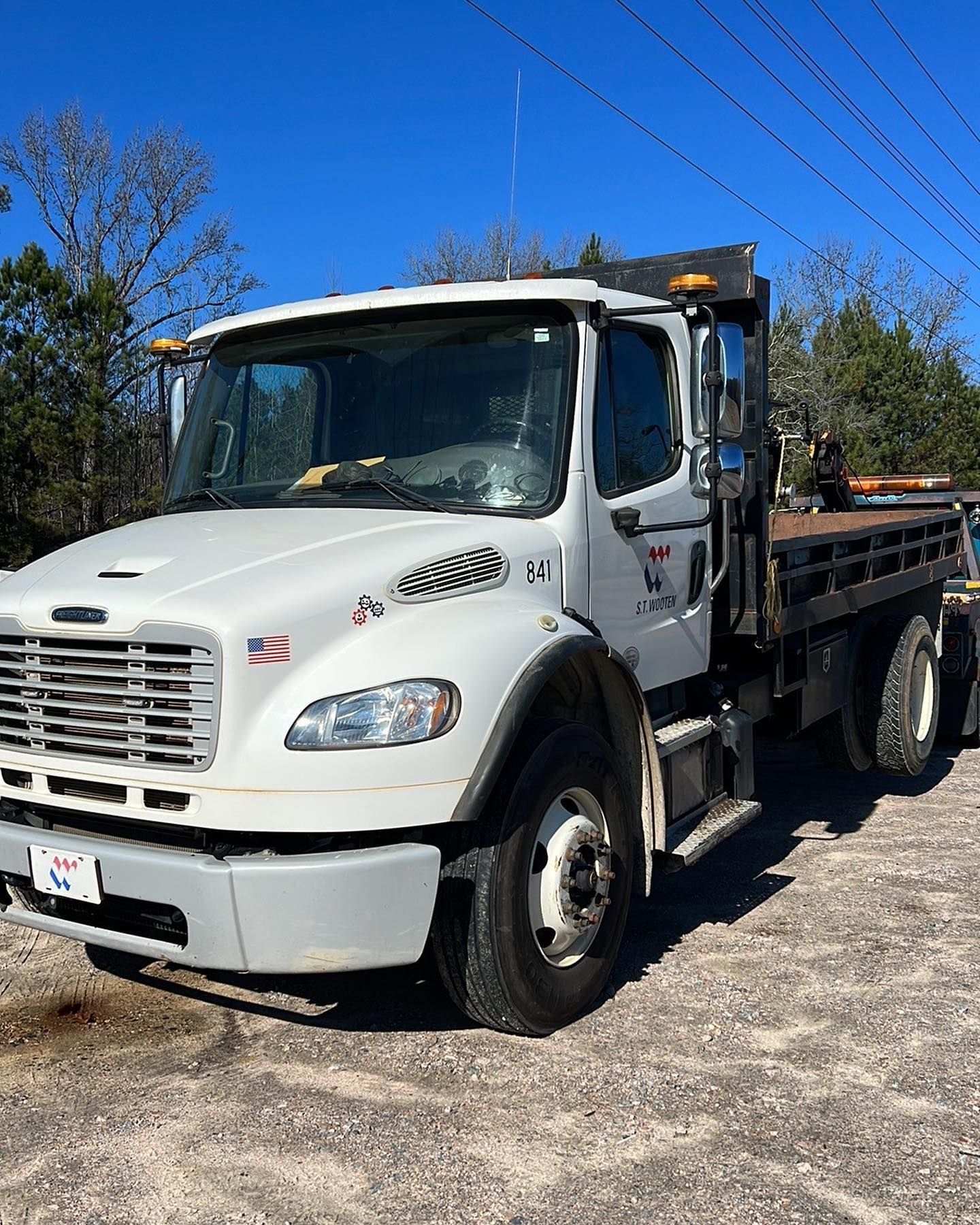 A white truck with a flatbed is parked on the side of the road.
