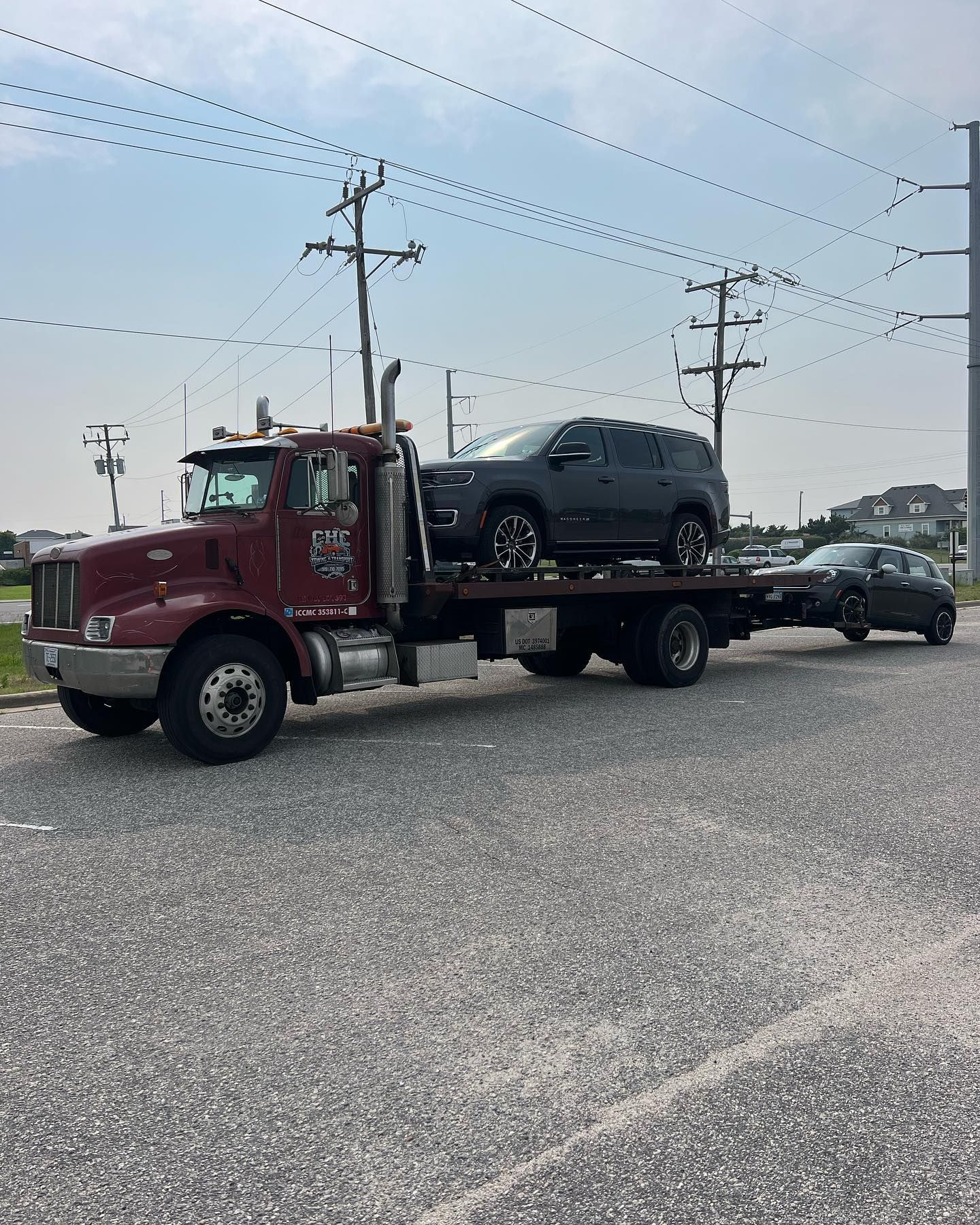 A red tow truck is towing a black suv and a black car.