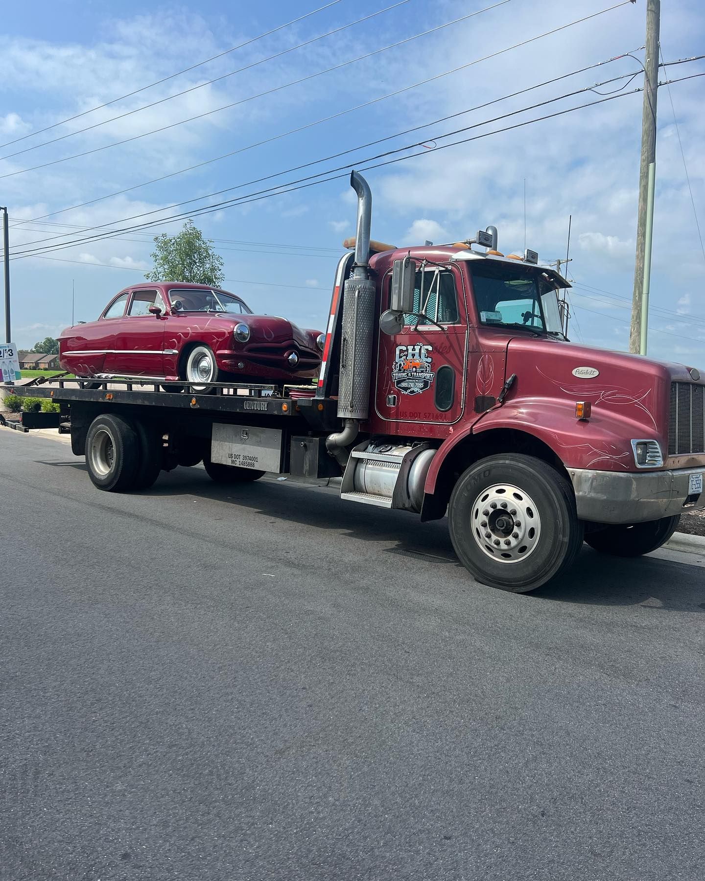 A red tow truck is carrying a red car on the back.