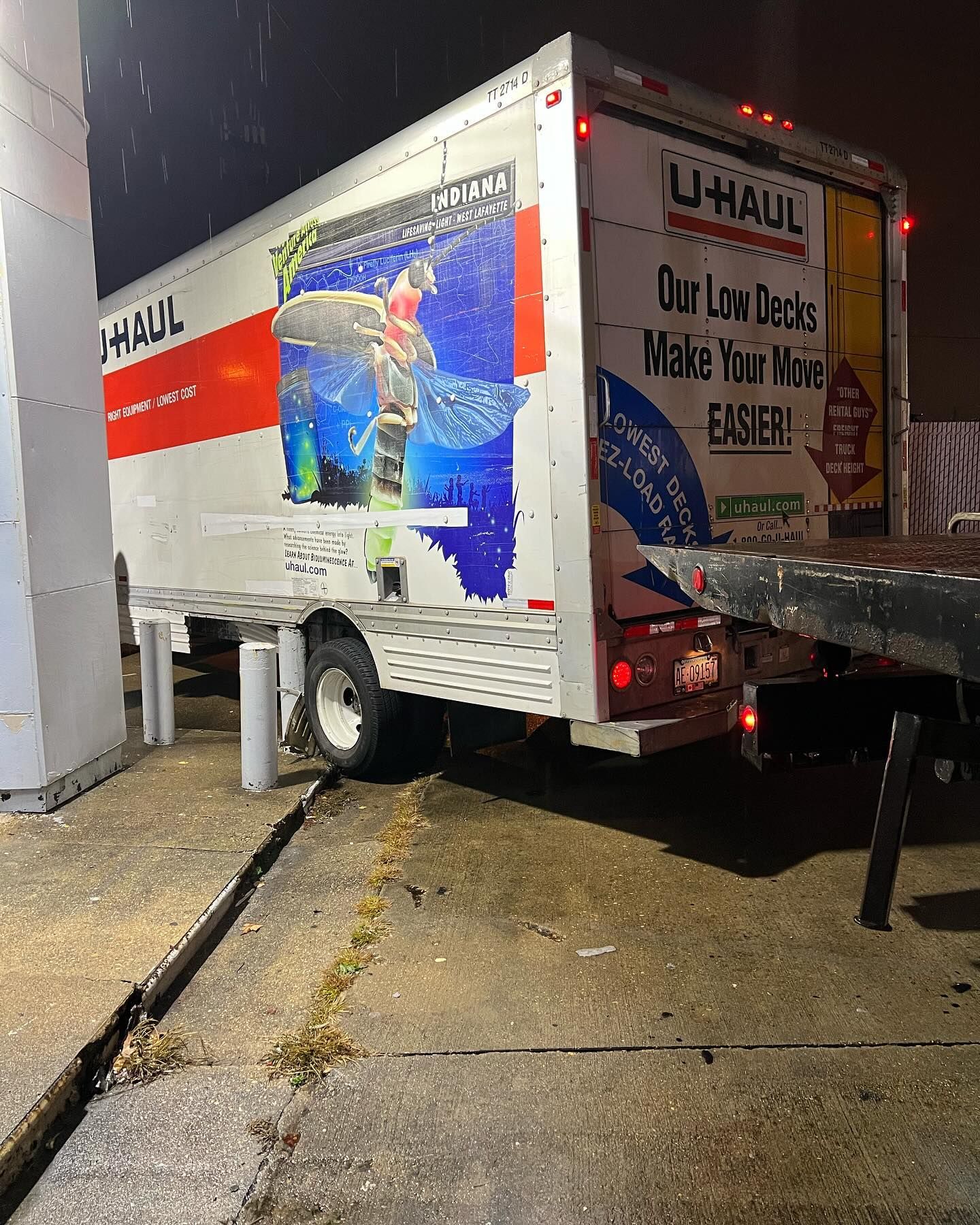A uhaul truck is parked on the side of the road at night.