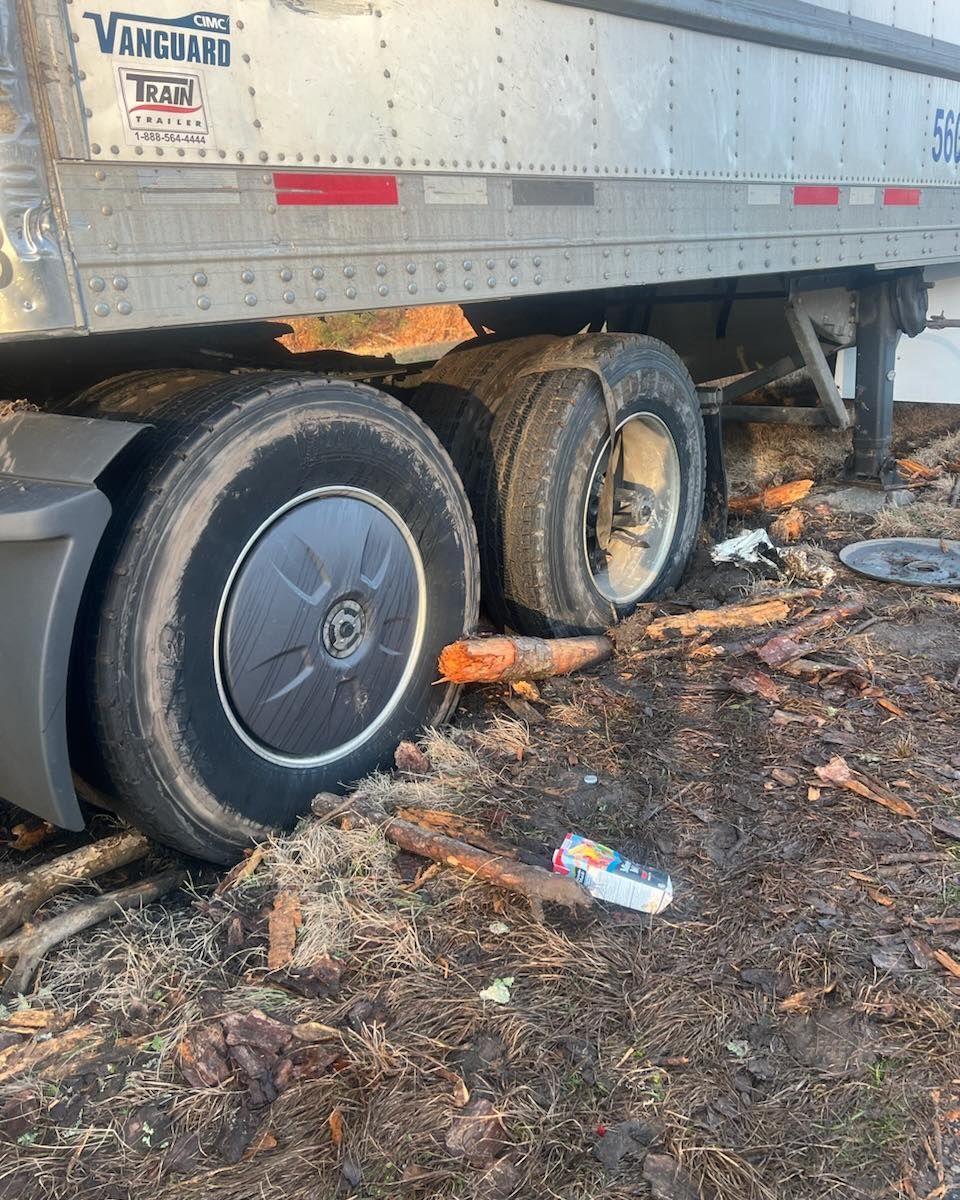 A semi truck with a flat tire is sitting on the ground.