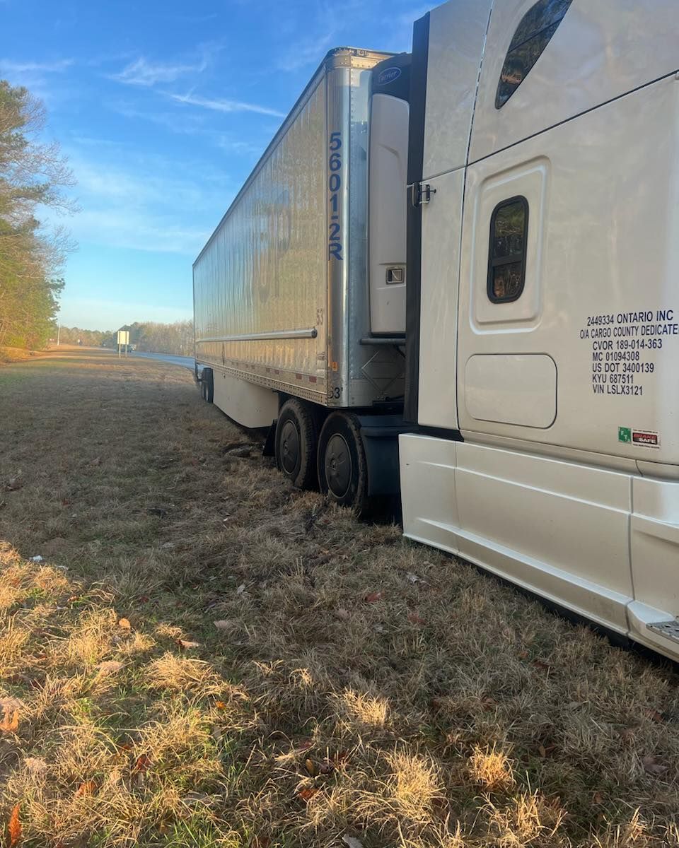 A semi truck is sitting in the middle of a field.