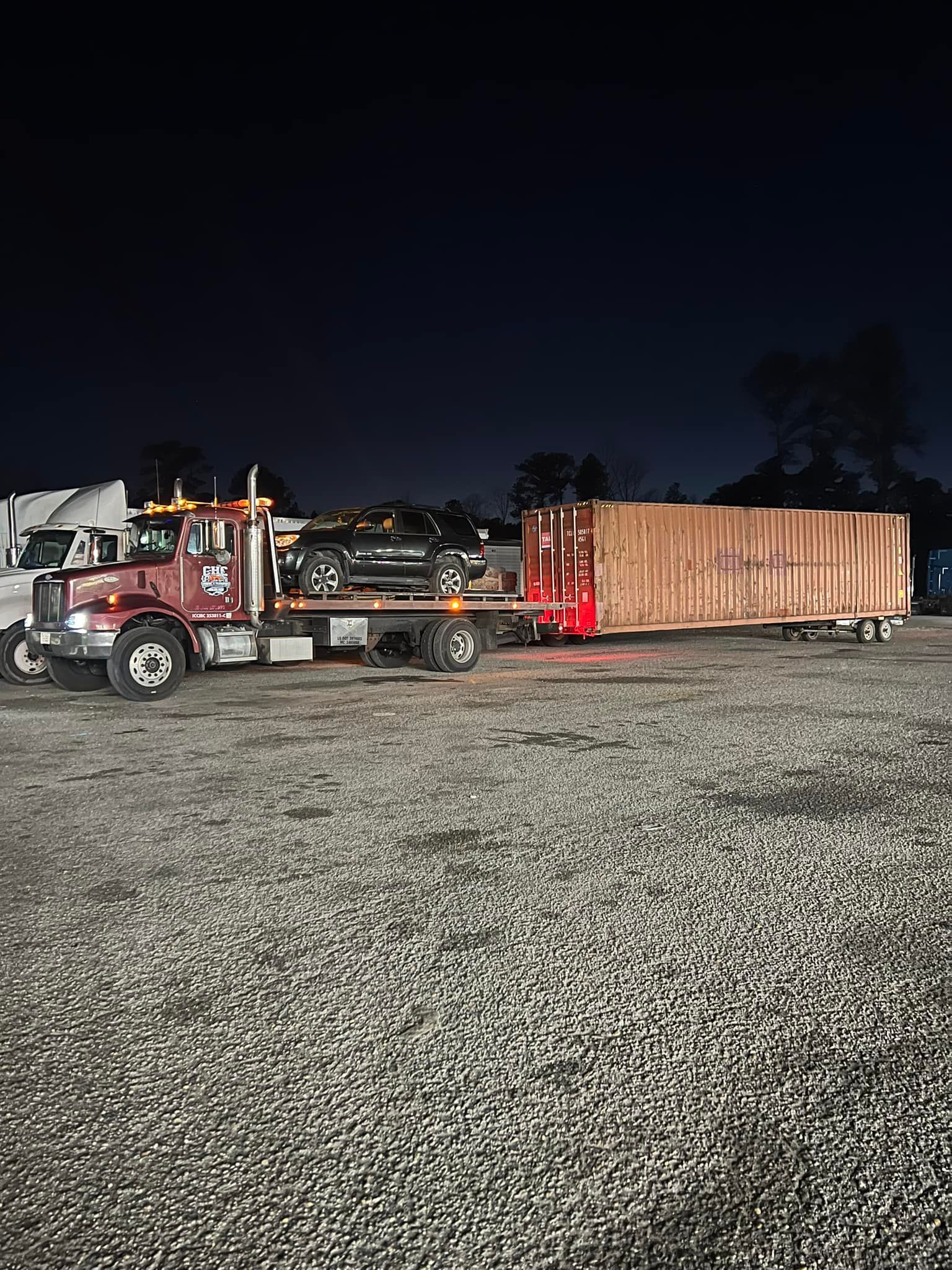 A semi truck is driving down a gravel road at night.
