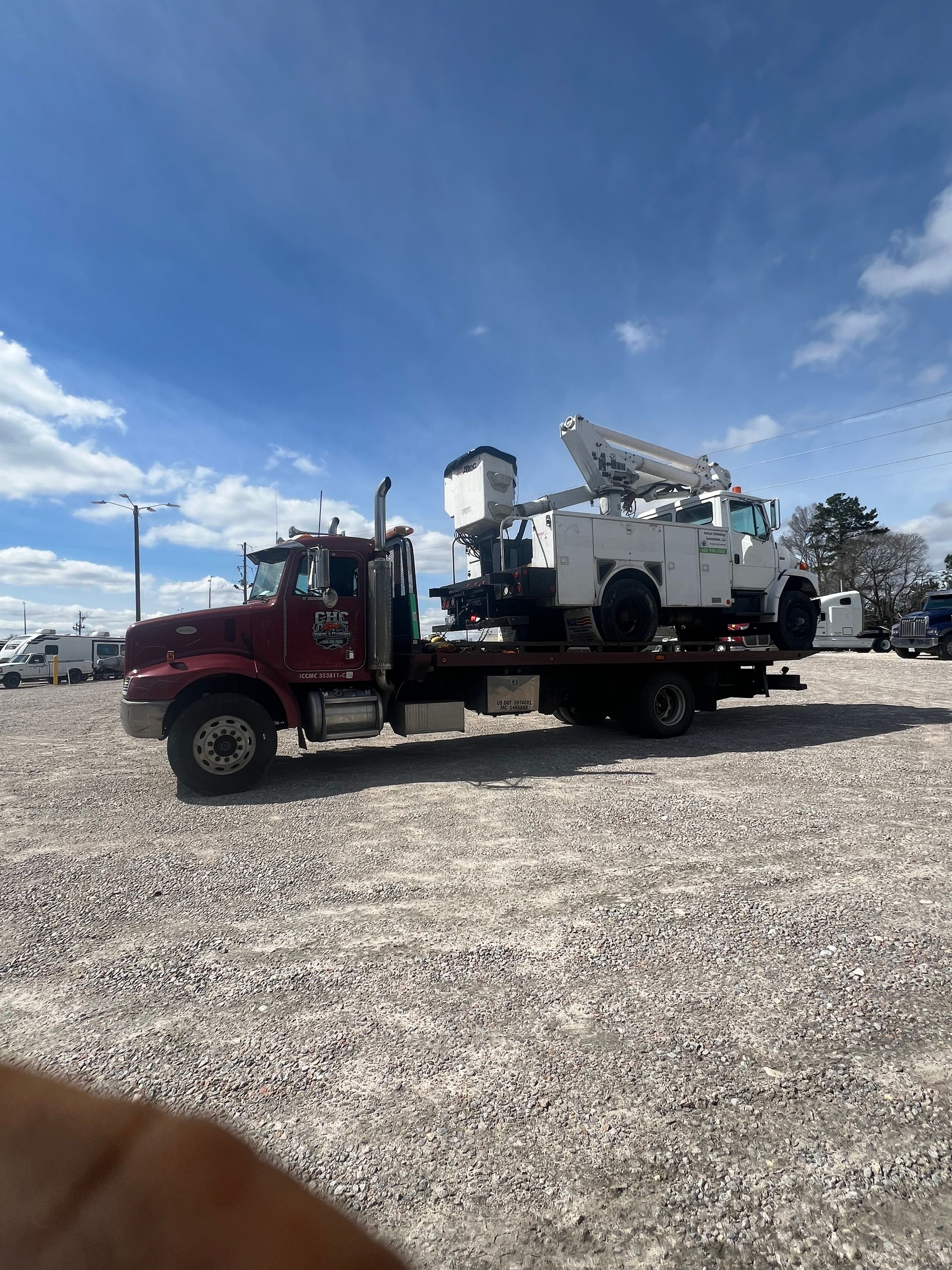 A red tow truck is carrying a white truck on the back of it.