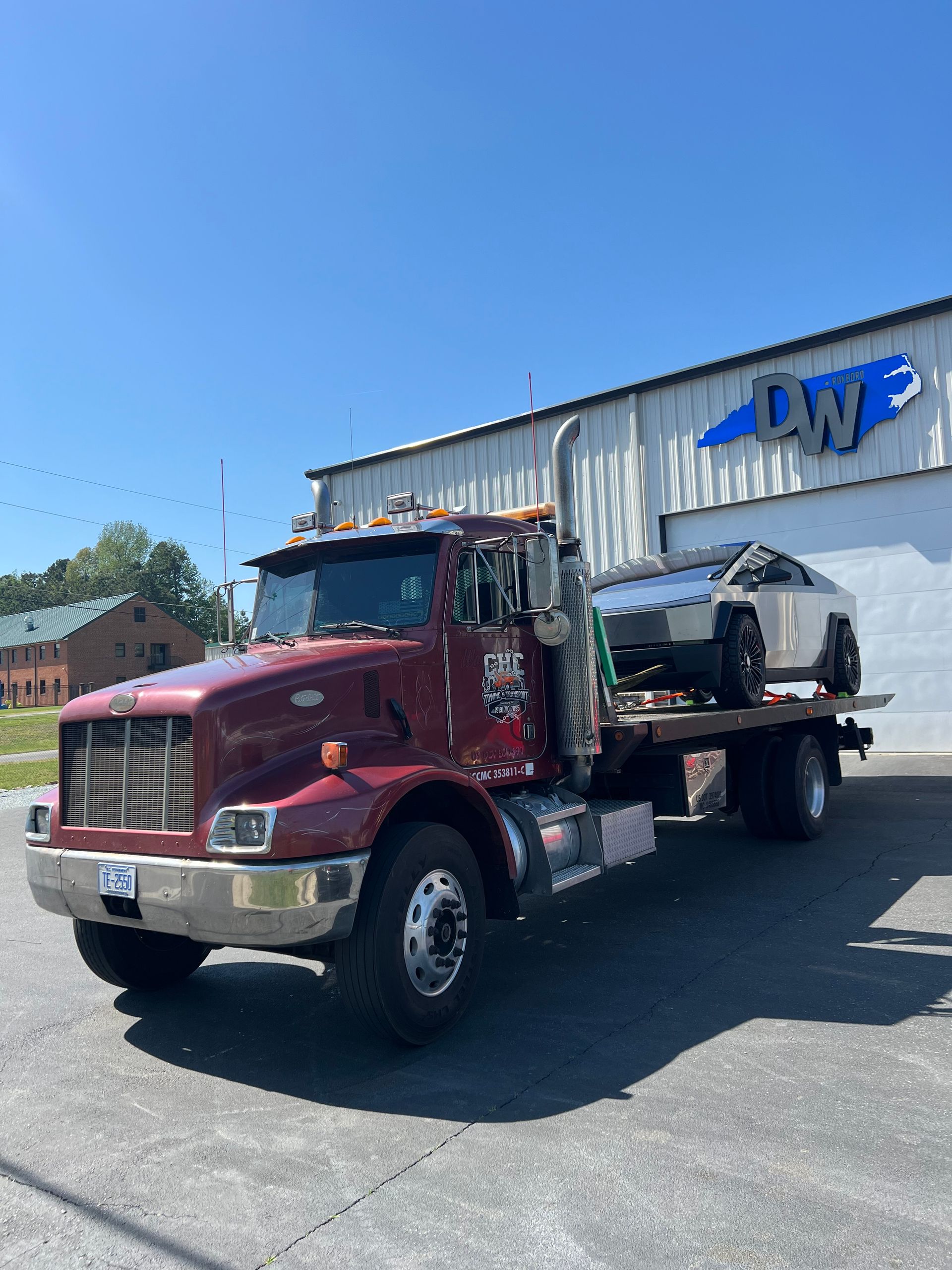 A red tow truck with a car on the back is parked in front of a building.