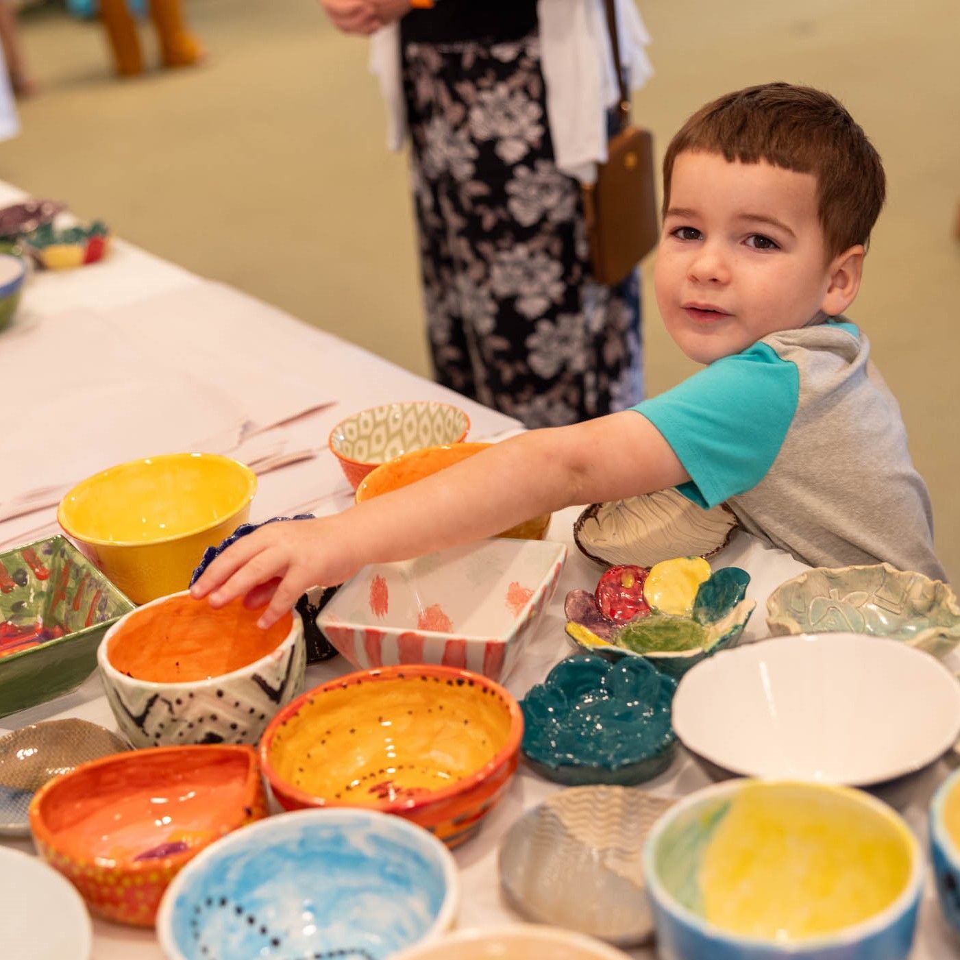 child selecting hand-painted ceramic bowls at empty bowls palm beach