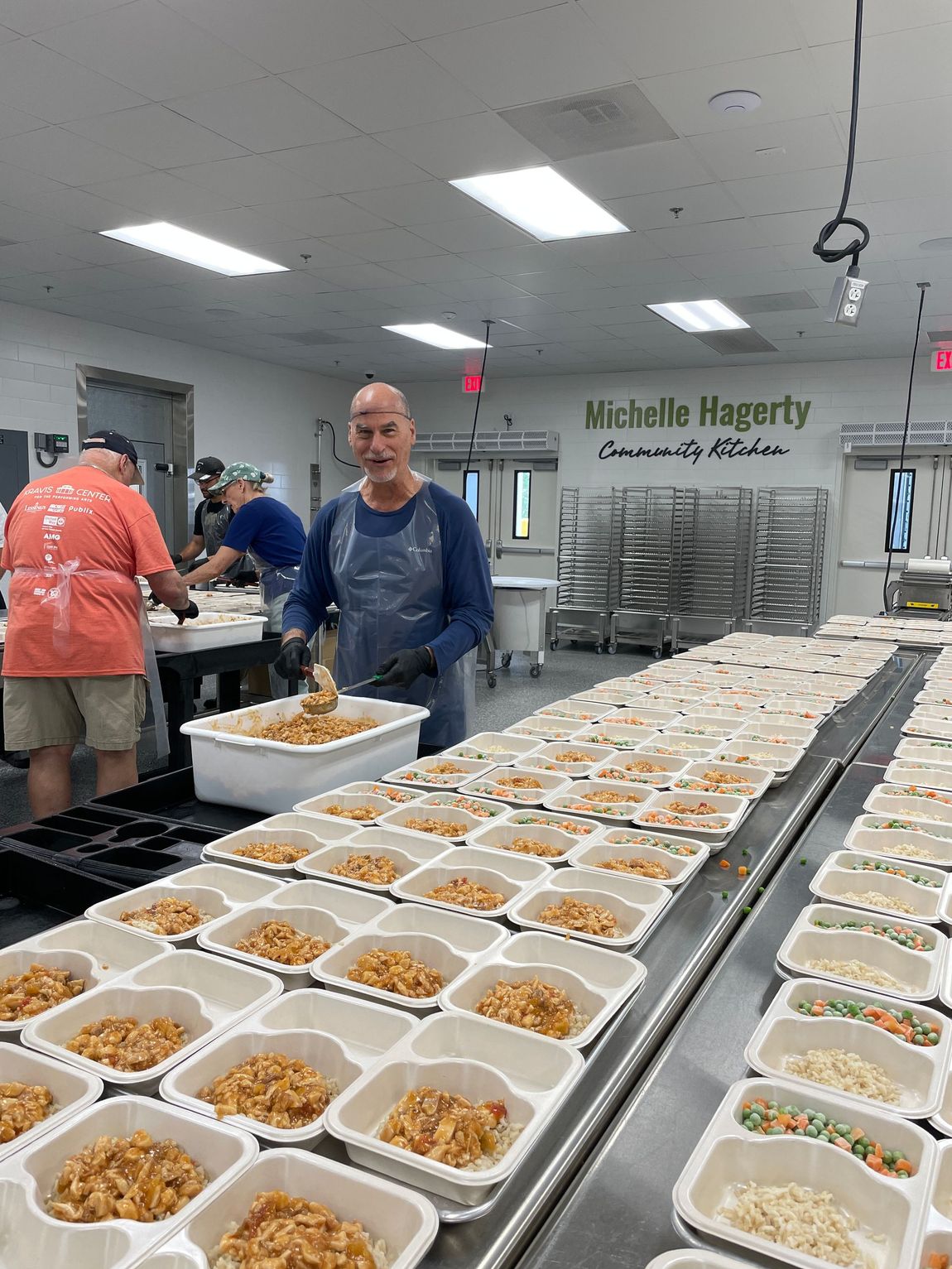 volunteer packing meals in two-department meal containers in the michelle hagerty community kitchen at palm beach county food bank