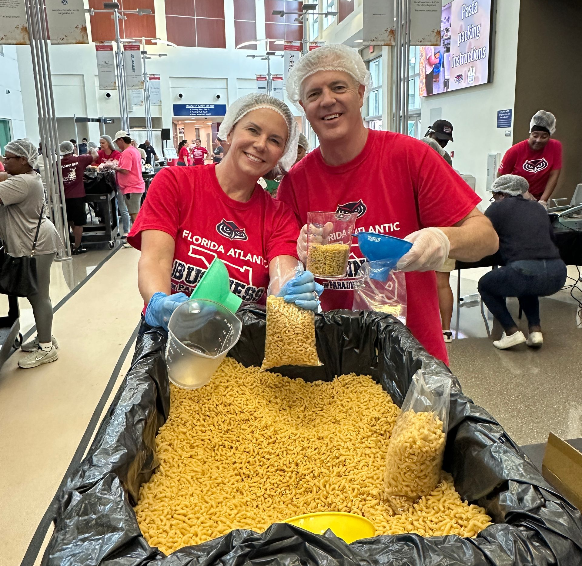 Two FAU volunteers packing pasta
