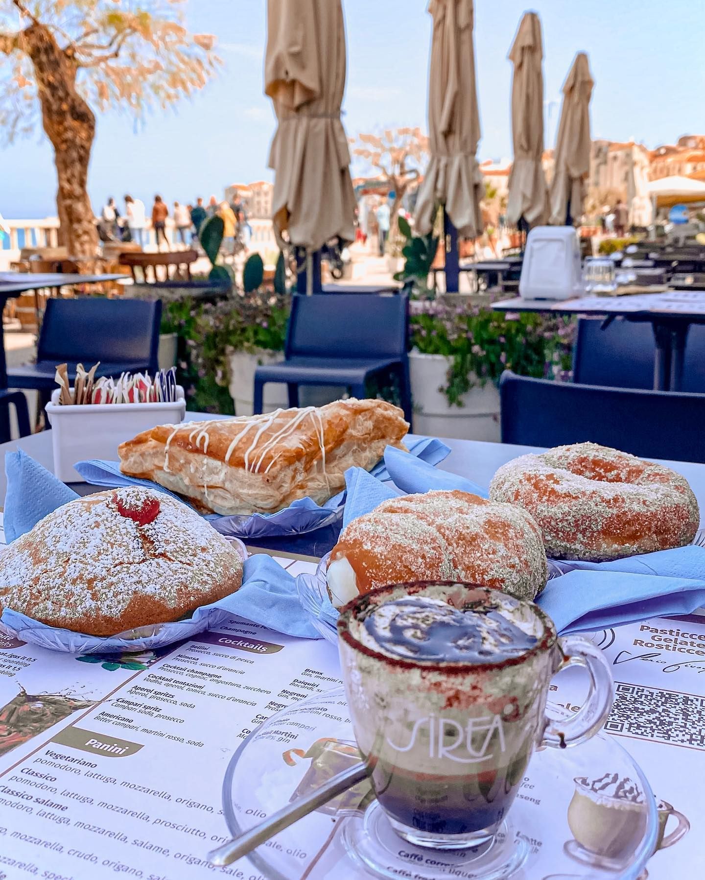 Pasticcini e caffè su un tavolo con arredamento da bar all'aperto.
