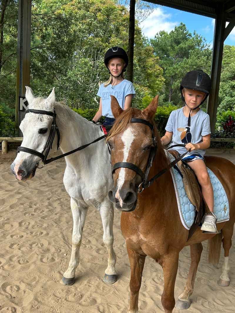 Two Young Girls Are Riding Horses in a Dirt Arena — Merrypark Equestrian Centre In Eumundi, QLD