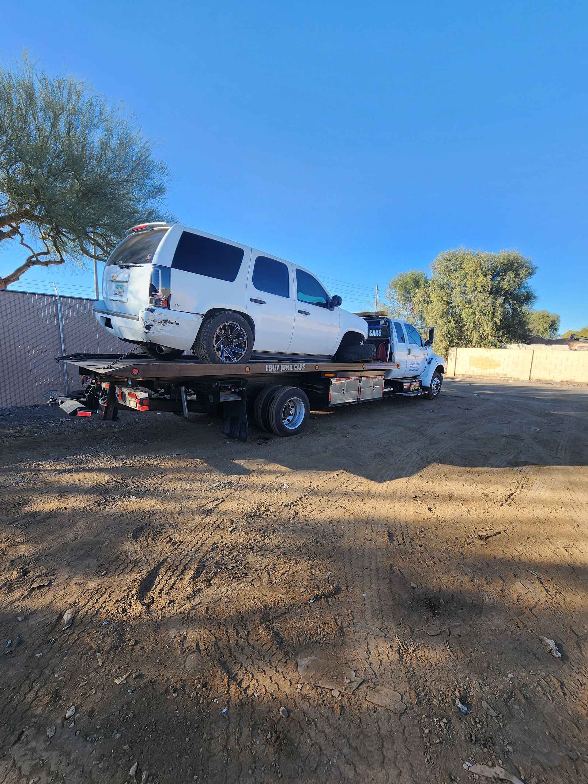 Red hot rod being towed on a flatbed tow truck. The truck is white.
