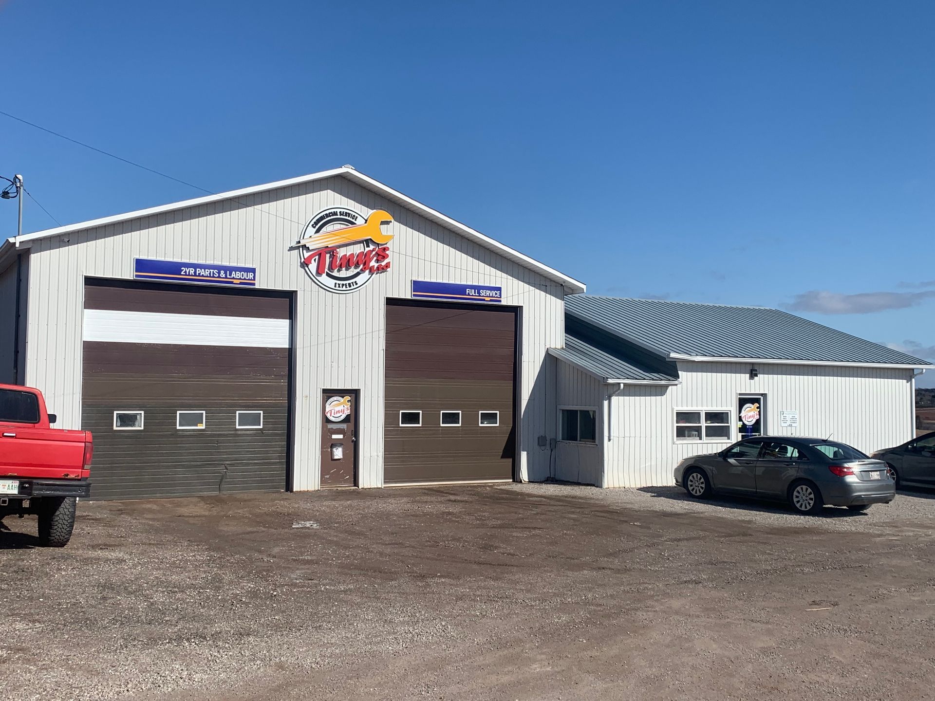 A red truck is parked in front of a garage. | Tiny's Automotive
