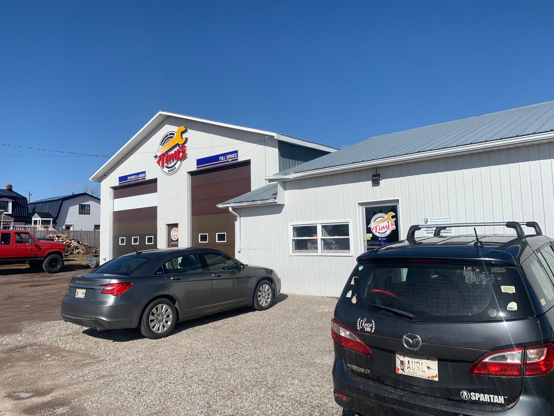 Two cars are parked in front of a garage. | Tiny's Automotive