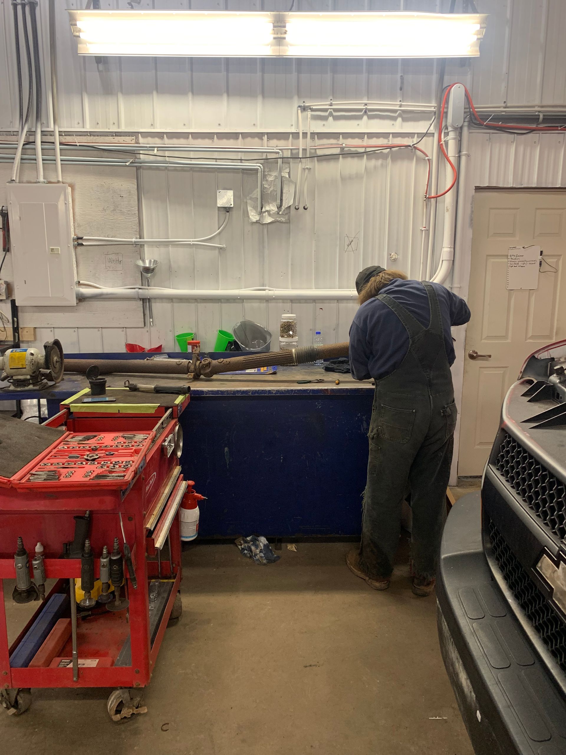 A man is working on a car in a garage. | Tiny's Automotive