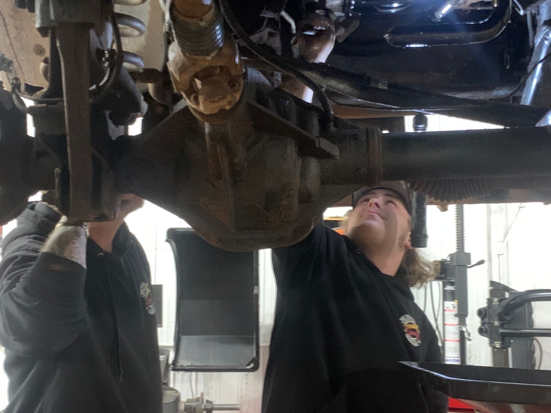 Two men are working on the underside of a vehicle | Tiny's Automotive