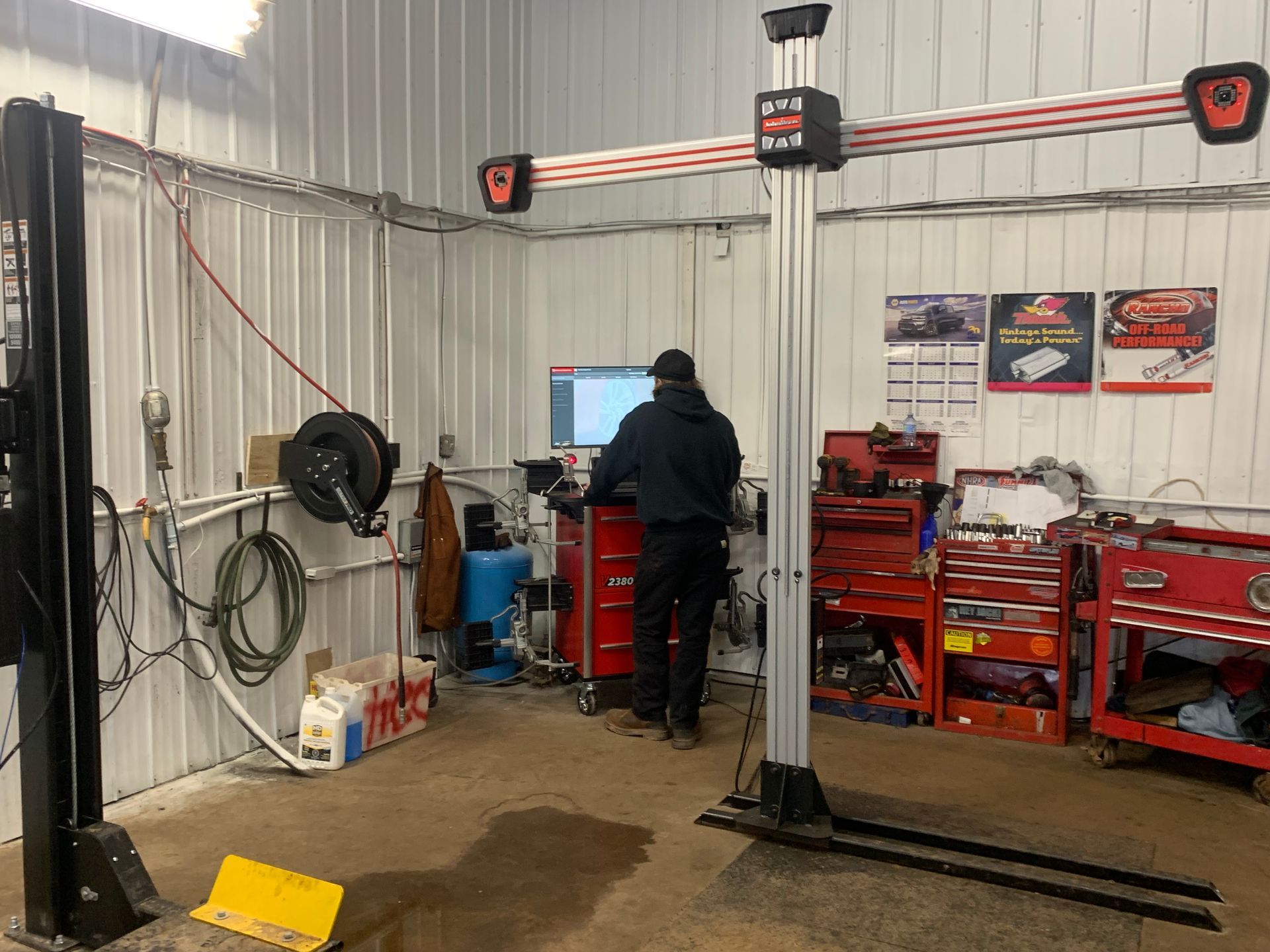 A man is working on a computer in a garage. | Tiny's Automotive