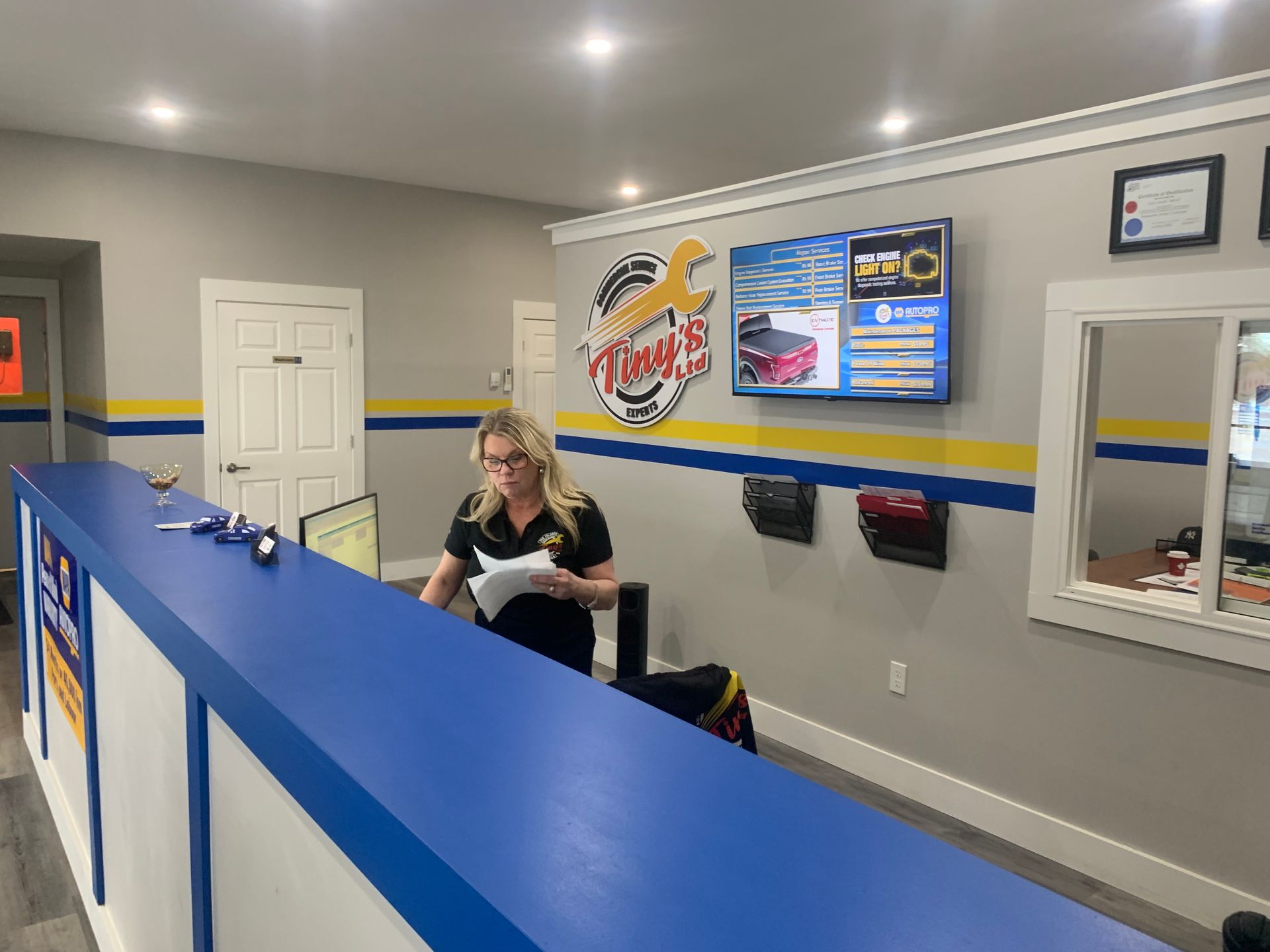 A woman is standing at a counter in a car dealership. | Tiny's Automotive