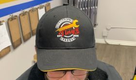 A man wearing a black baseball cap with a wrench on it. | Tiny's Automotive