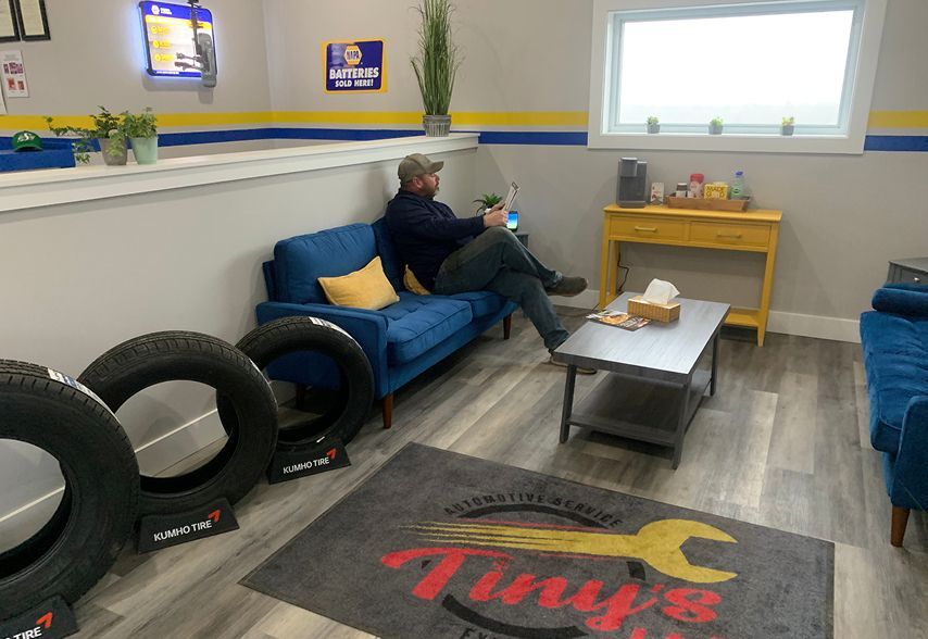 A man is working on the engine of a car in a garage. | Tiny's Automotive