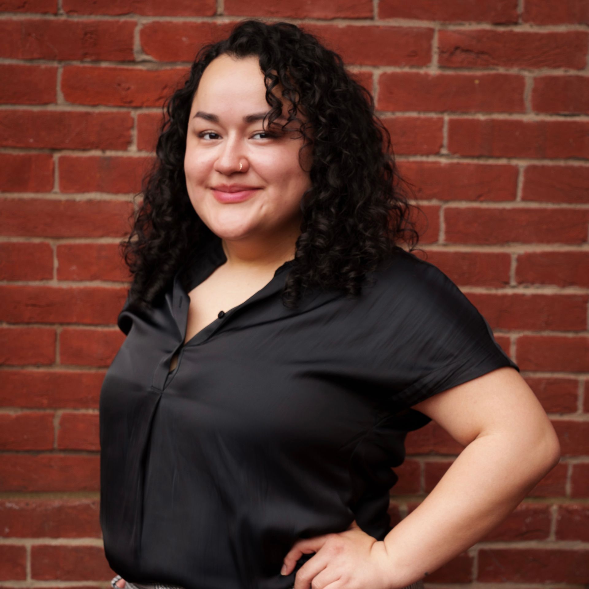 A woman is sitting at a desk with a laptop and a vase of flowers.