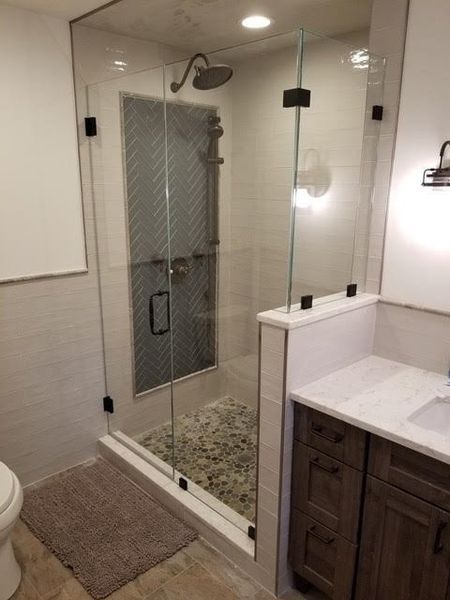 A bathroom with a walk in shower and a sink.