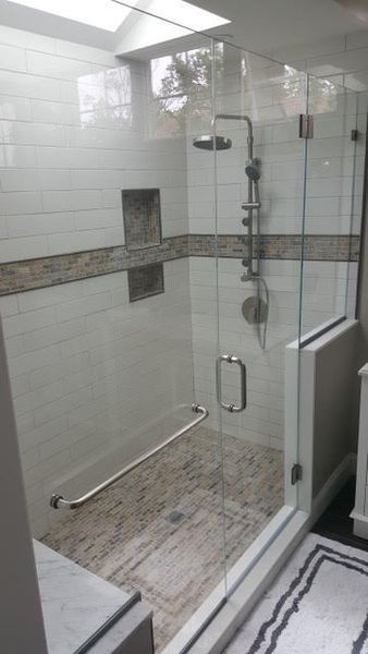 A bathroom with a walk in shower with a glass door.