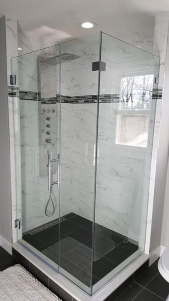 A bathroom with a walk in shower with a glass door.