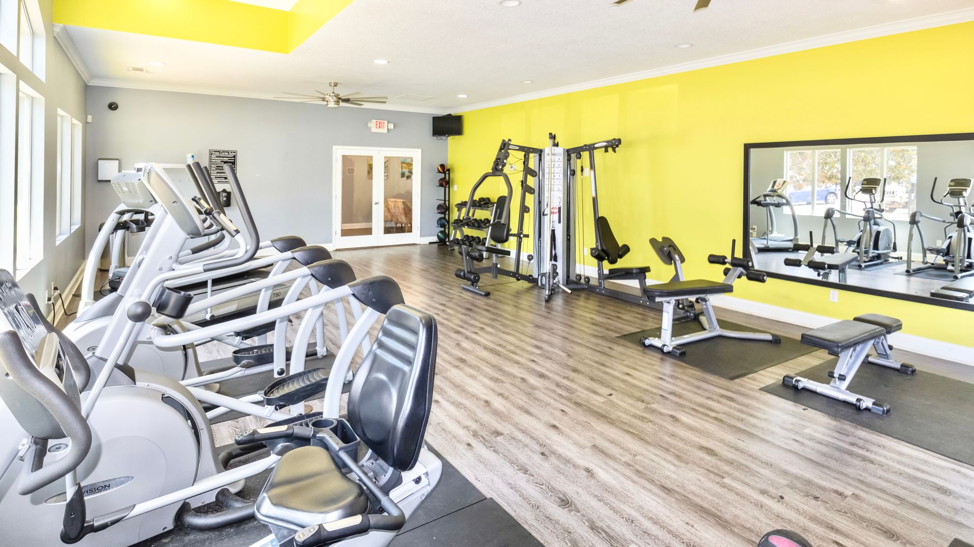 A large gym with a lot of exercise equipment and a large mirror.