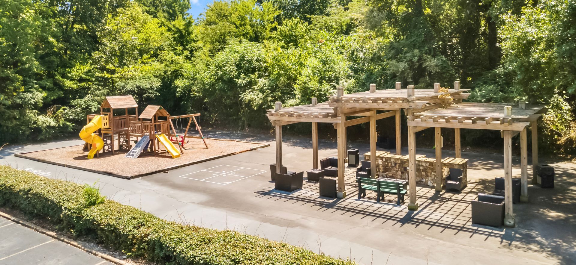 An aerial view of a playground in a park surrounded by trees.