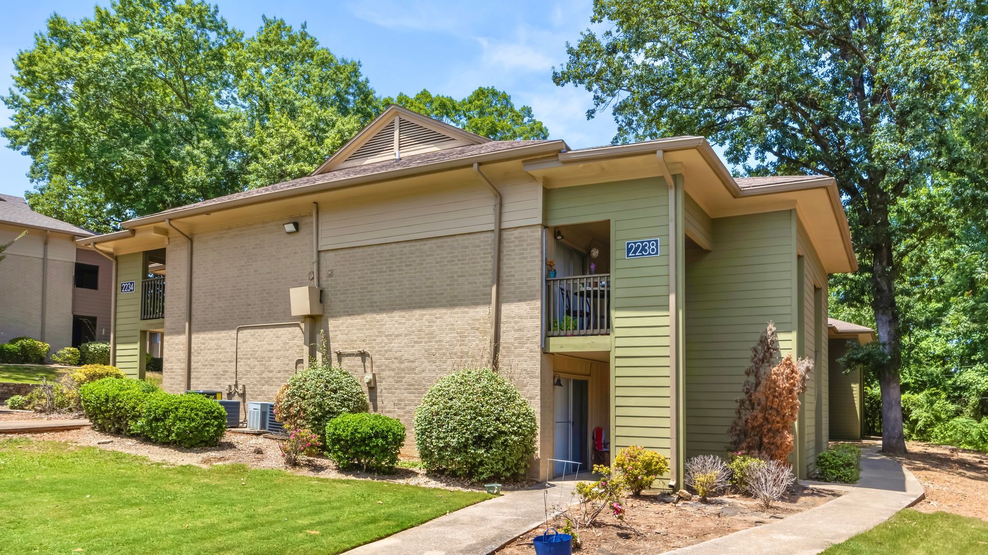 A large apartment building with a lush green lawn in front of it.