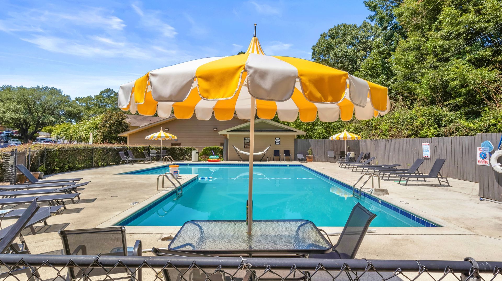 A large swimming pool with a table and chairs and an umbrella.