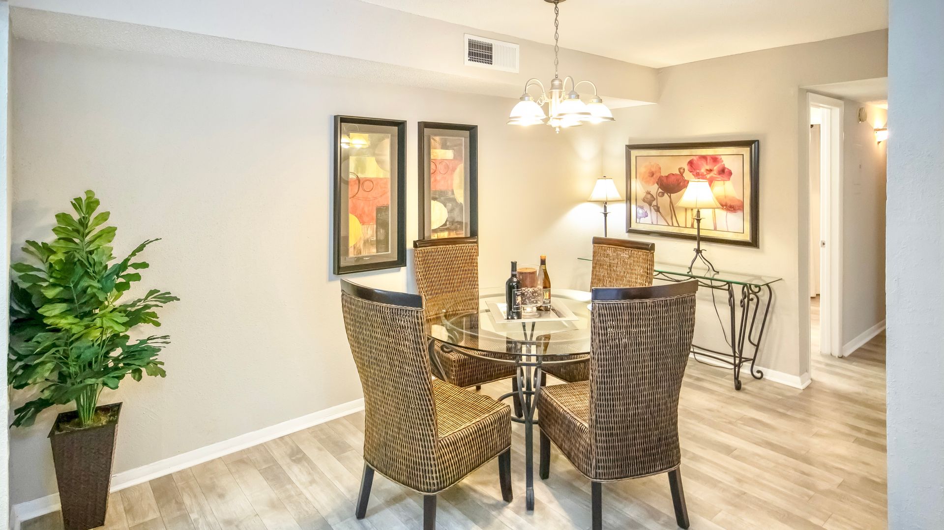 A dining room with a table and chairs and a potted plant.