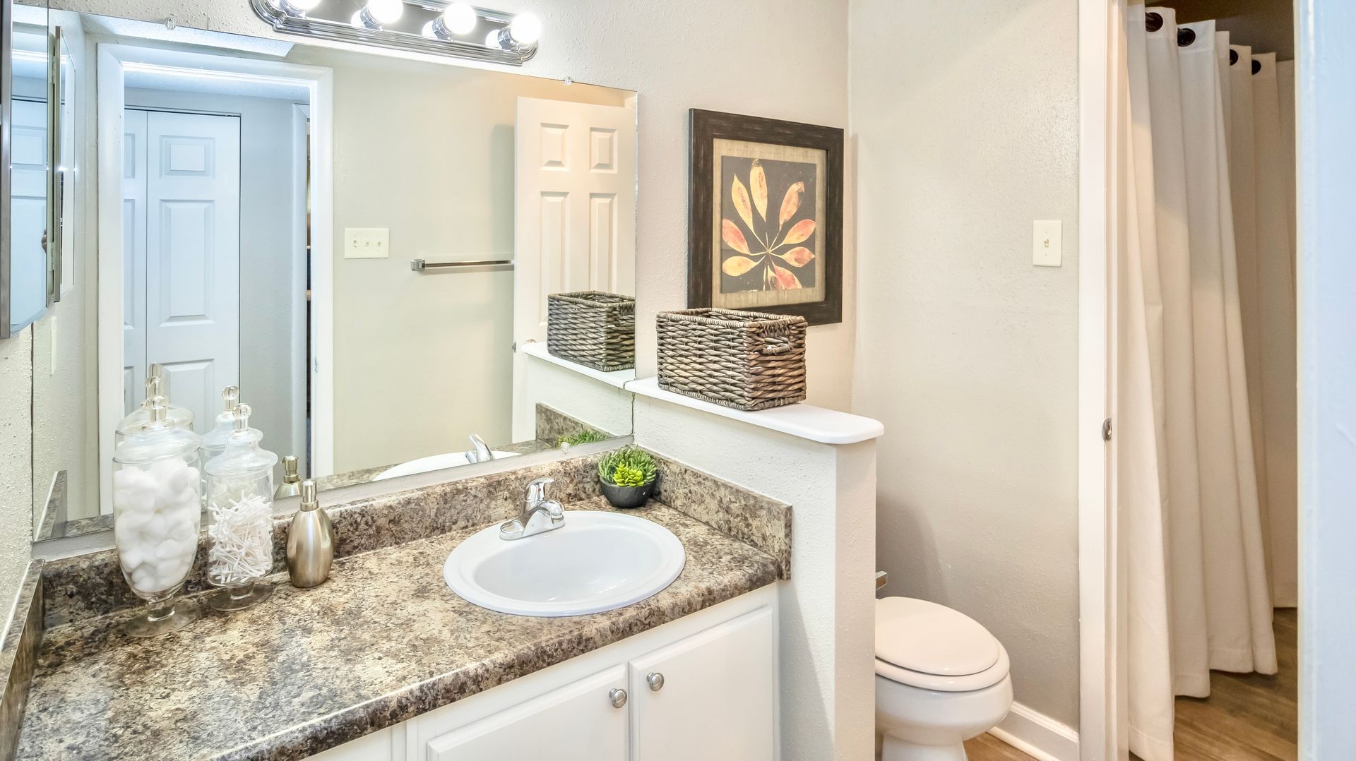 A bathroom with a sink , toilet and mirror.