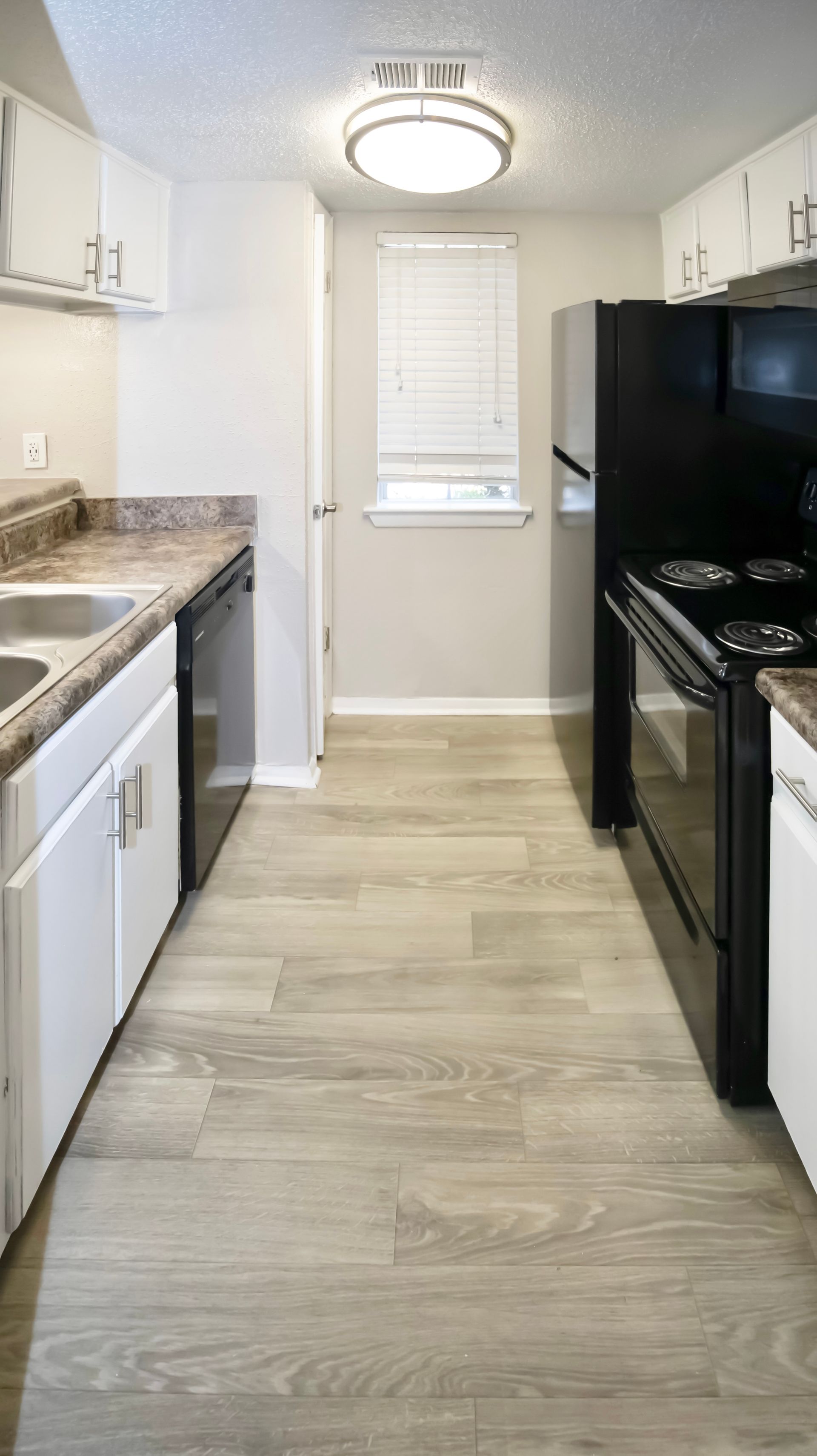 A kitchen with a stove , refrigerator , dishwasher and sink.