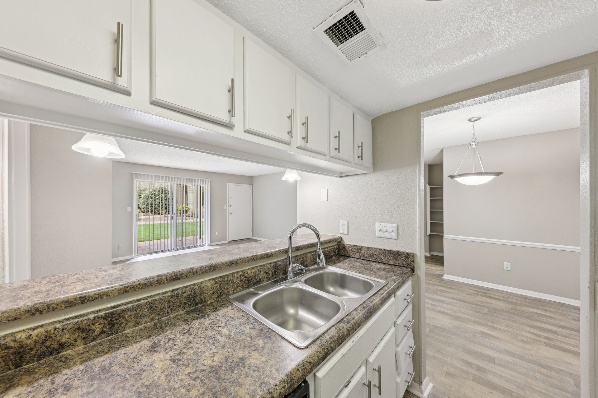 A kitchen with two sinks , granite counter tops and white cabinets.