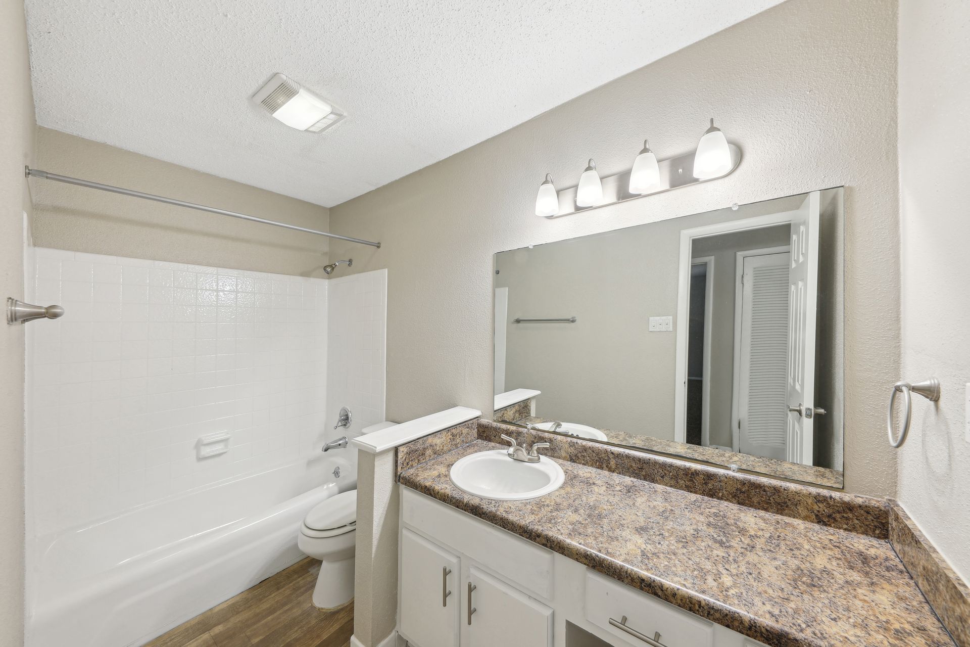 A bathroom with a sink , toilet , bathtub and mirror.