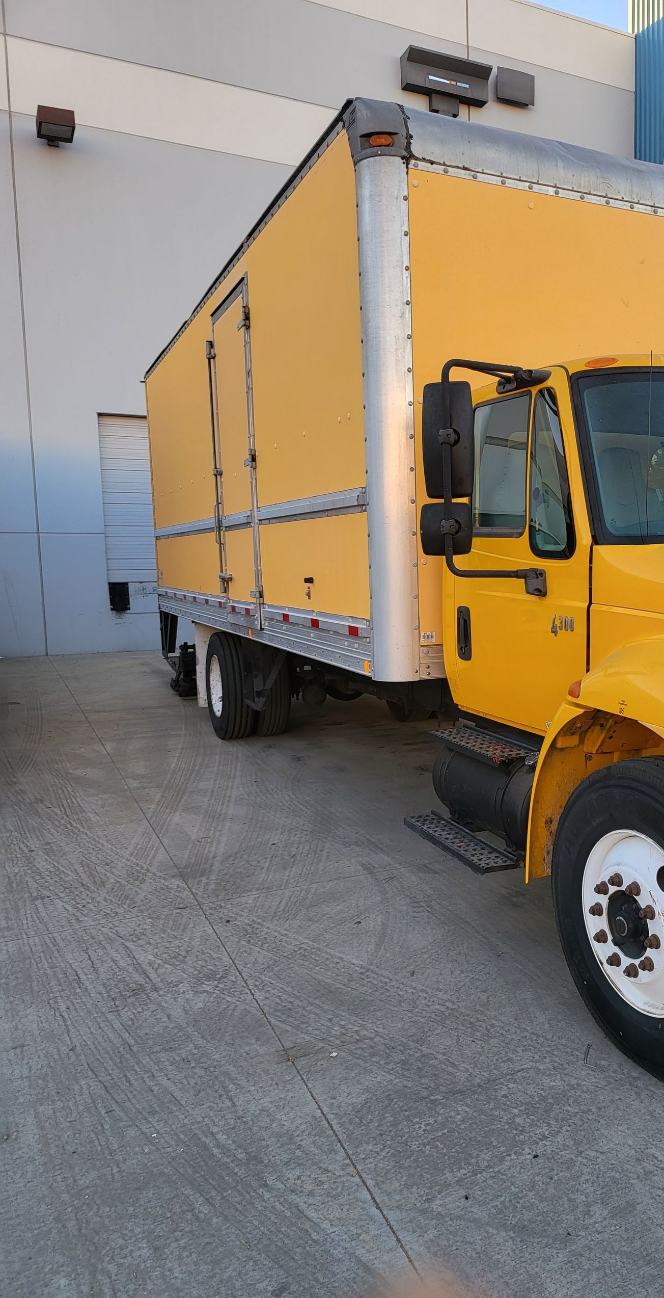 A row of semi trucks are parked in a gravel lot.