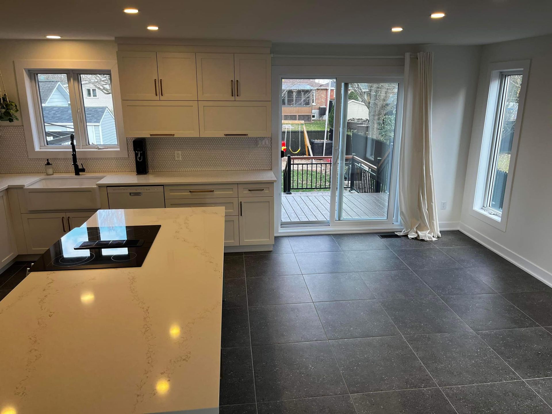 Une cuisine avec des armoires blanches et un grand îlot au milieu de la pièce.